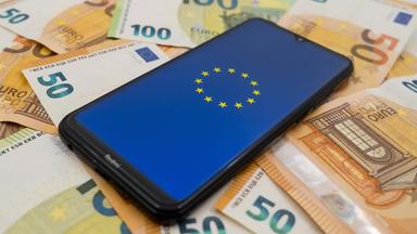 Die Europafahne auf dem Display eines Smartphones, das auf 50 Euro-Scheinen liegt.