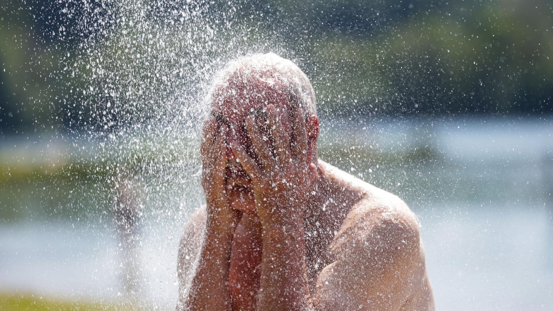 Ein Mann erfrischt sich unter einer Dusche an einem Badesee | Thomas Warnack/dpa