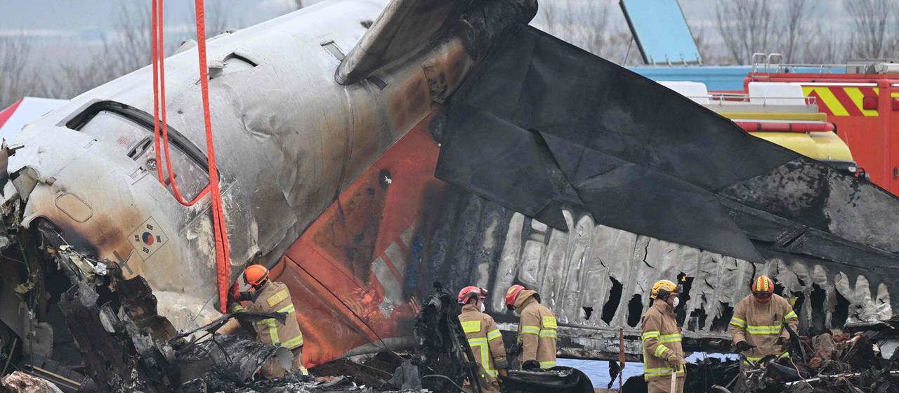 Feuerwehrleute und Bergungsteams arbeiten nach einem Absturz an einem Flugzeugwrack Muan International Airport, Südkoera.