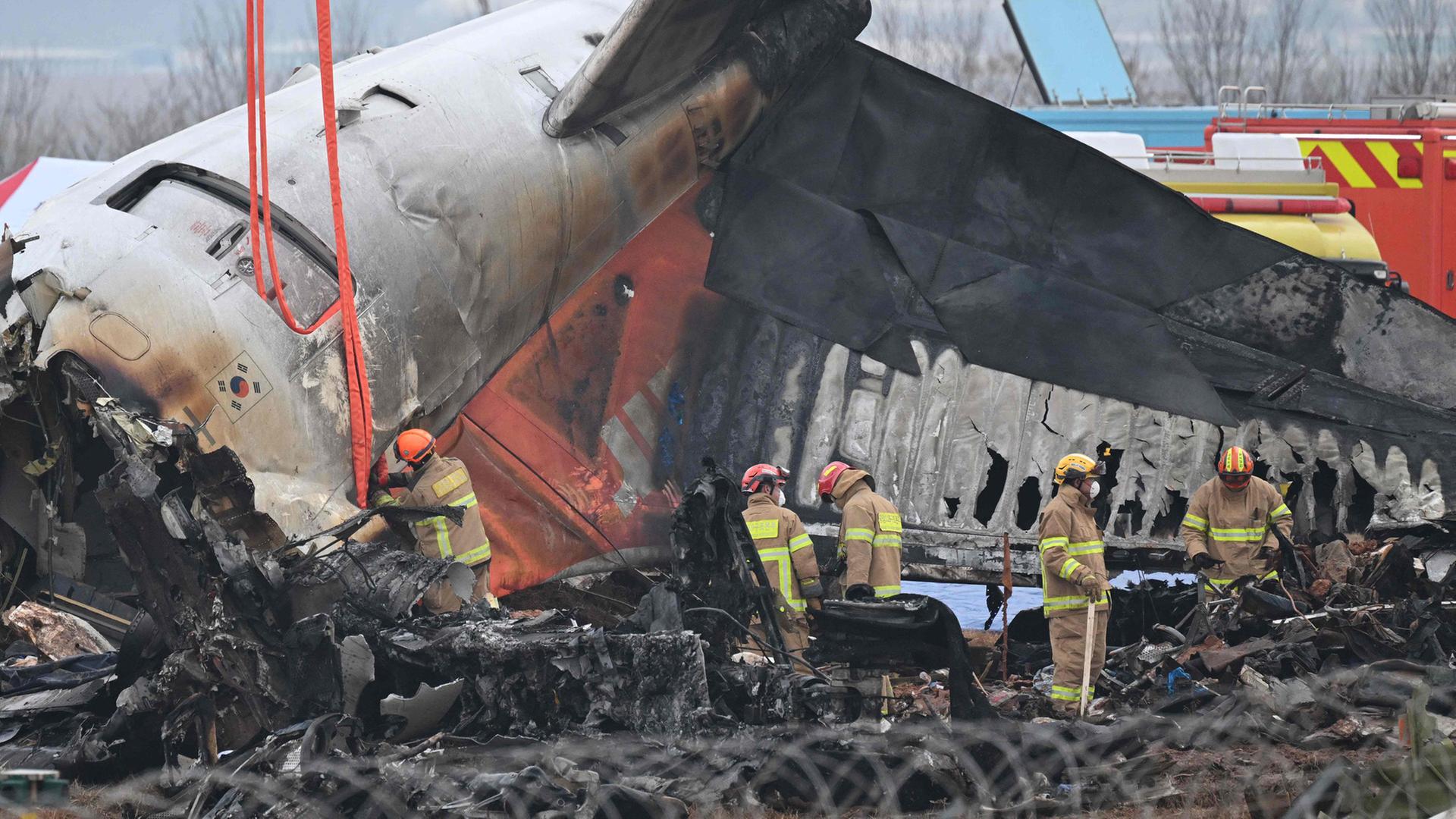 Feuerwehrleute und Bergungsteams arbeiten nach einem Absturz an einem Flugzeugwrack Muan International Airport, Südkoera. | AFP