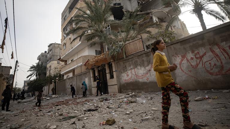 Eine Außenansicht zeigt ein beschädigtes Haus nach einem israelischen Luftangriff im Flüchtlingslager Rafah im südlichen Gazastreifen - im Vordergrund ein Mädchen.