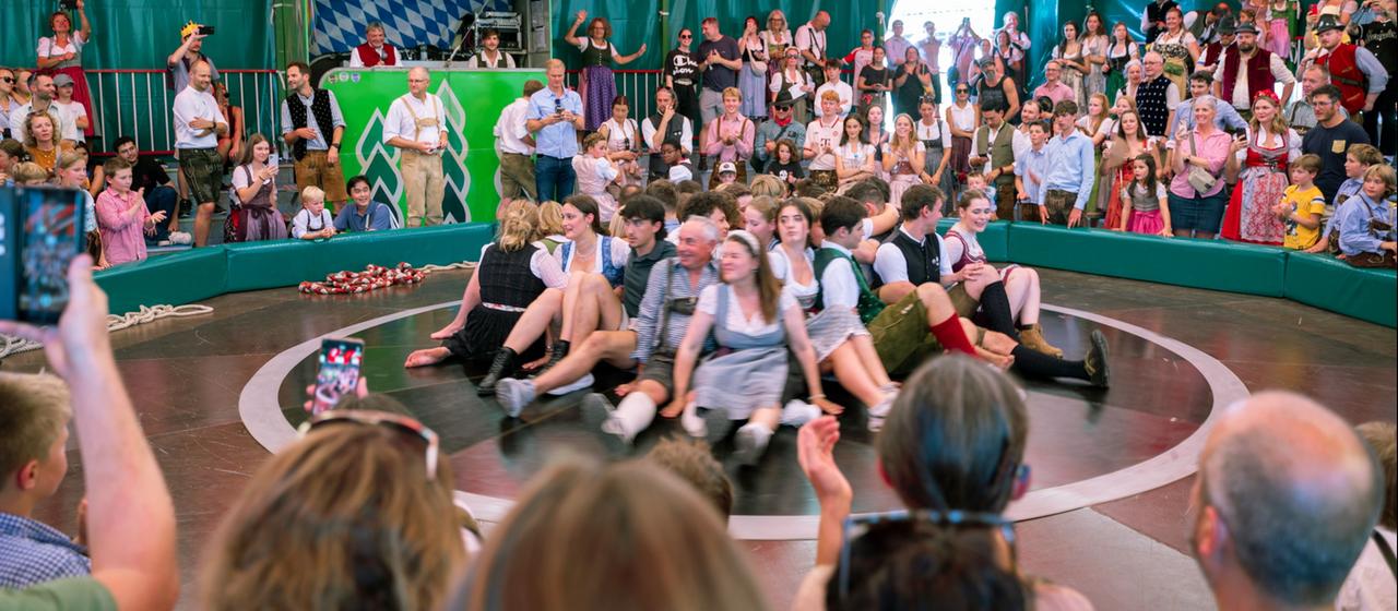 Besucherinnen und Besucher sitzen auf dem Teufelsrad auf dem Oktoberfest.