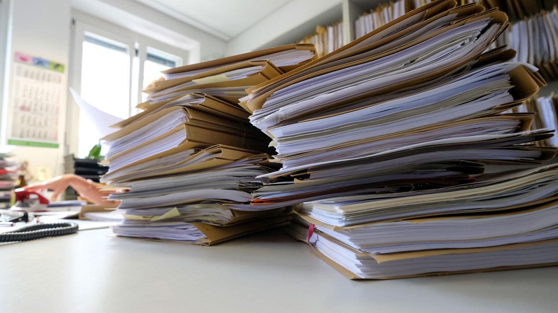 Ein Stapel mit Akten liegt auf dem Schreibtisch. | picture alliance/dpa