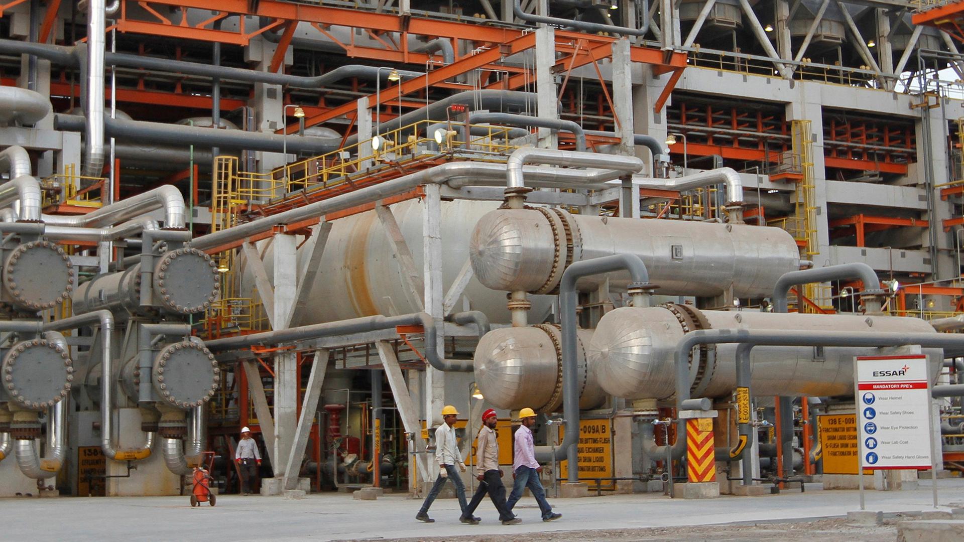 Mitarbeiter gehen an Rohren in der Vadinar Raffinerie in Indien vorbei (Archivbild von 2012). | REUTERS