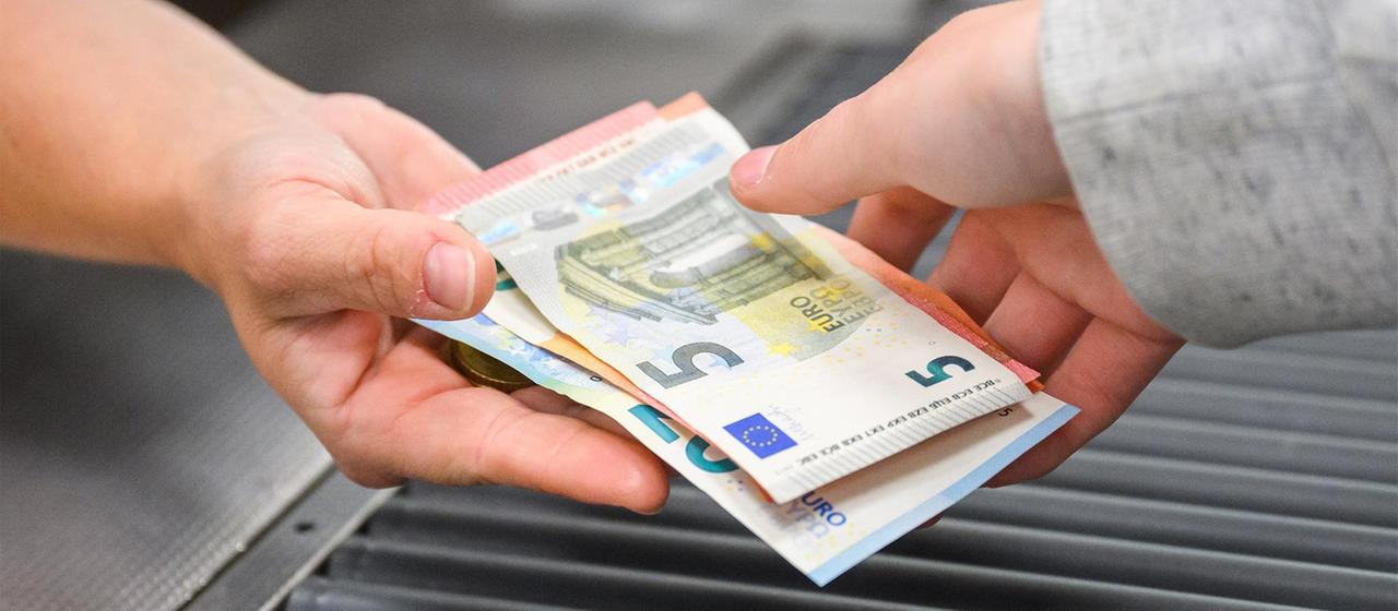 Eine Kassiererin gibt einer Kundin Geld an der Kasse eines Supermarktes.