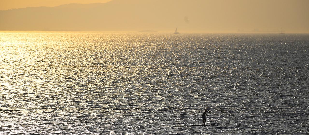Ein Mann paddelt an einem Strand südlich von Athen (Griechenland) auf seinem SUP.