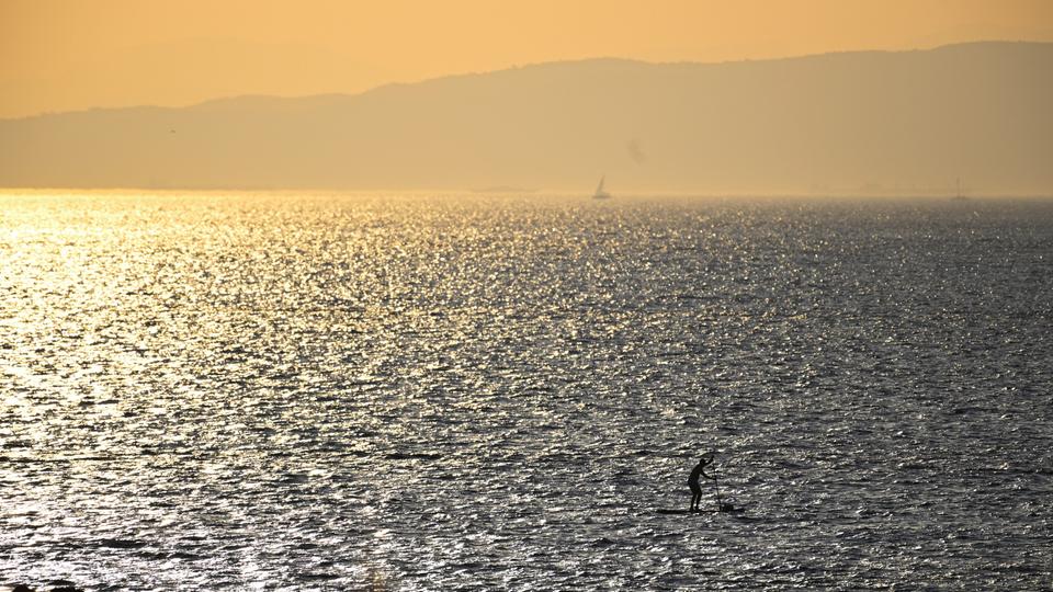 Ein Mann paddelt an einem Strand südlich von Athen (Griechenland) auf seinem SUP.