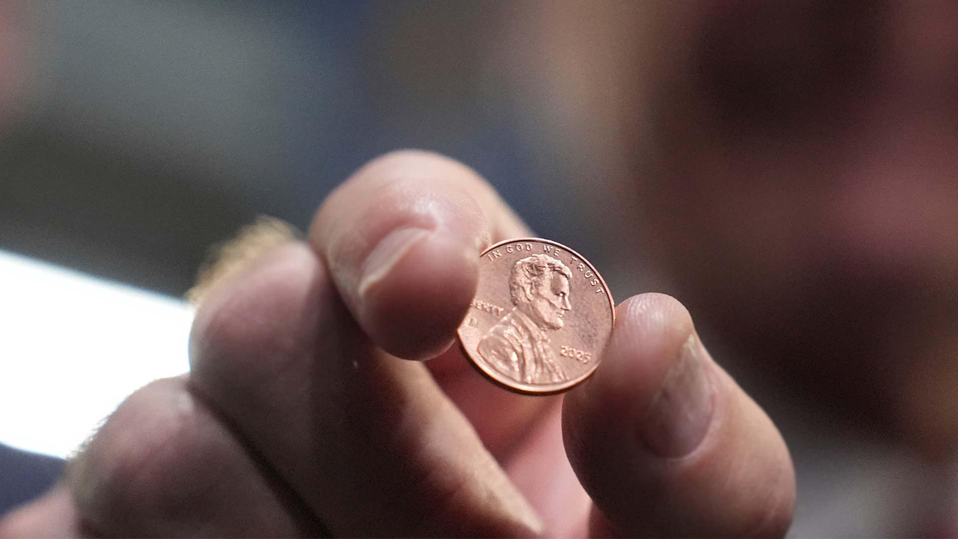 US-Schatzmeister Brandon Beach hält einen der letzten in der US-Münzanstalt gepressten Pennies.  | picture alliance/dpa/AP