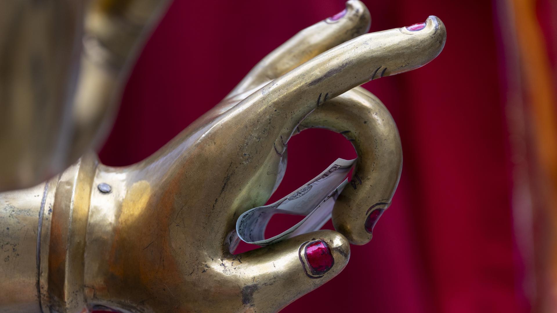 Geld liegt in der Hand einer Buddha-Statue. | EPA