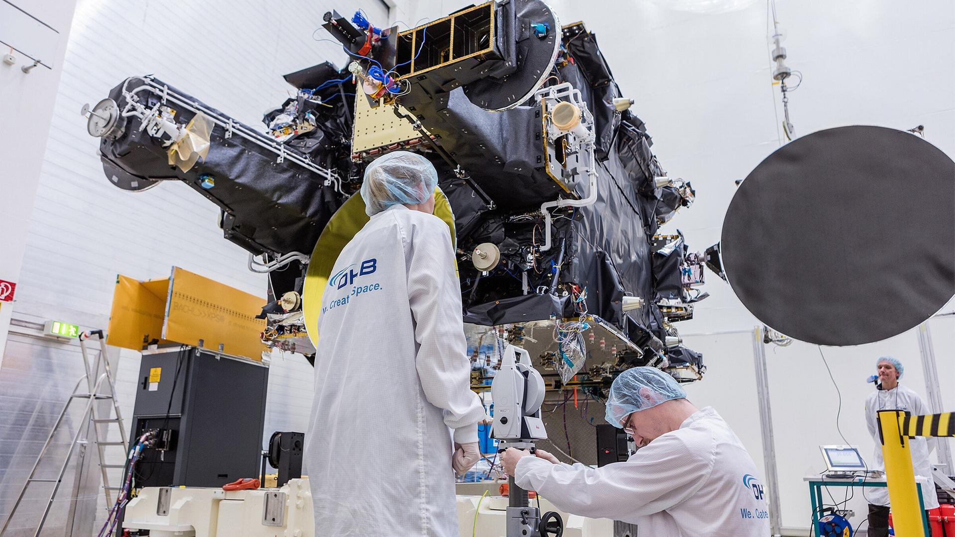 OHB Mitarbeiter prüfen einen Telekommunikationssatelliten (Archivbild). | picture alliance / OHB/OHB/dpa