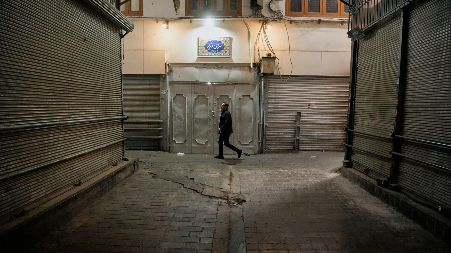 Ein Mann geht an geschlossenen Geschäften im fast leeren Basar Tajrish im Norden Teherans, Iran, vorbei. | AP