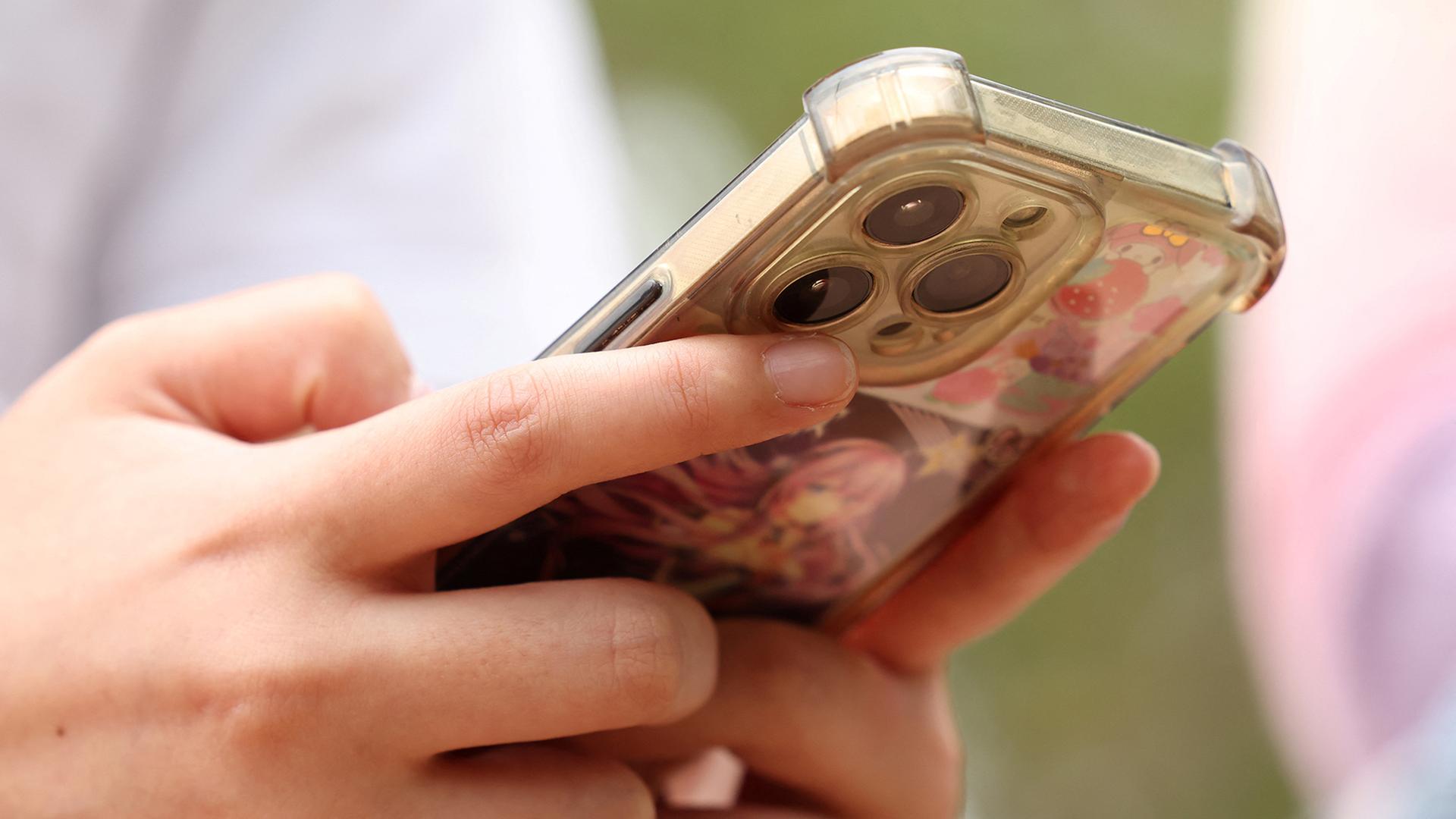 Ein Mädchen hält ein Handy in den Händen. | REUTERS