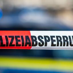 Ein Absperrband mit der Aufschrift "Polizeiabsperrung" ist vor einem Polizeiwagen aufgespannt.