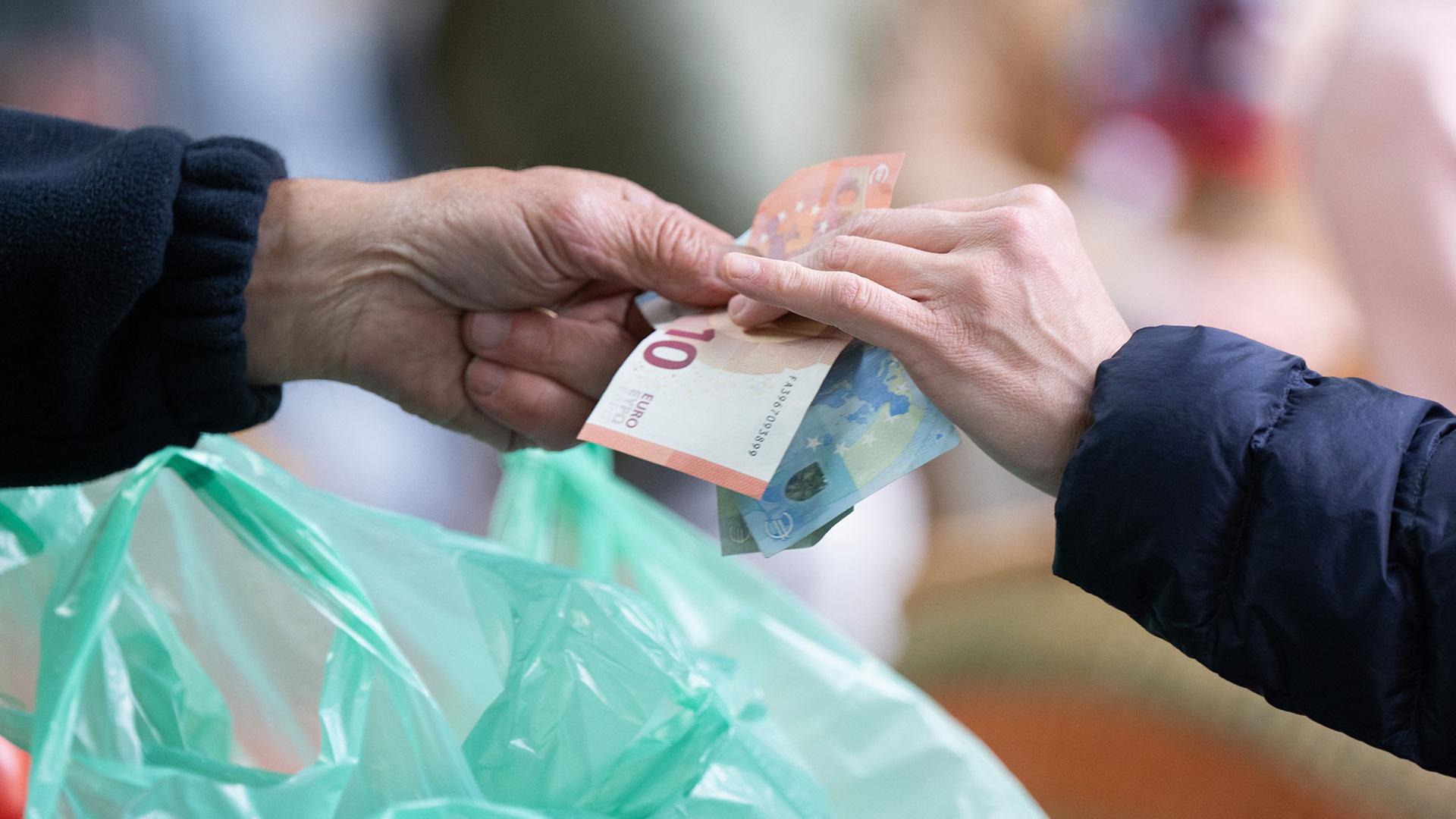 Eine Kundin bezahlt Ihren Einkauf auf einem Wochenmarkt mit Bargeld. | picture alliance/dpa