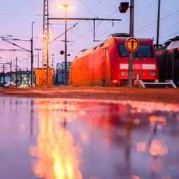 Eine Lok der Deutschen Bahn DB steht im Hauptbahnhof Hannover und spiegelt sich in einer Wasserfläche auf dem Bahnsteig.