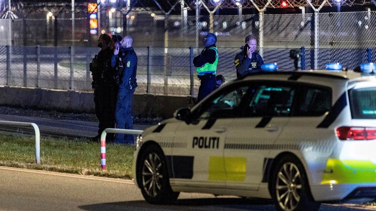 Ein Polizeiauto und mehrere Polizisten stehen am Flughafen in Kopenhagen.
