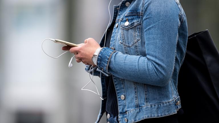 Eine junge Frau blickt auf ihr Smartphone.