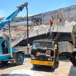 Rettungskräfte stehen auf Trümmern eines eingestürzten Gebäudes