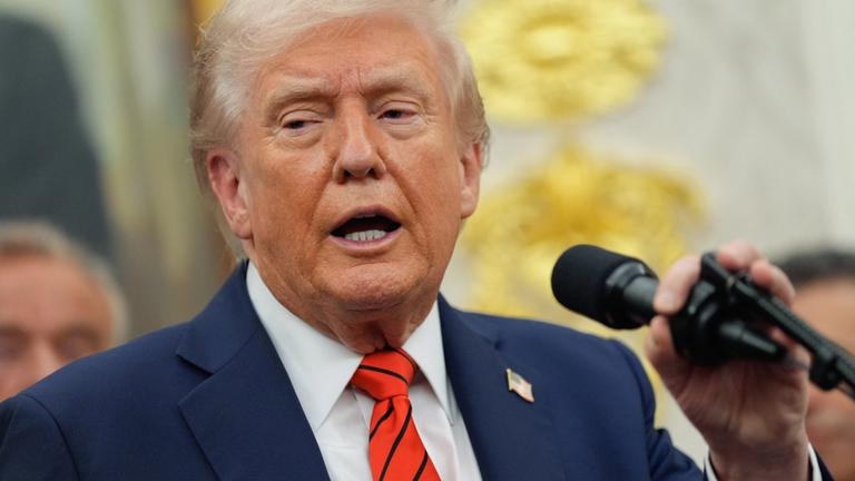 Donald Trump spricht in ein Mikrofon.