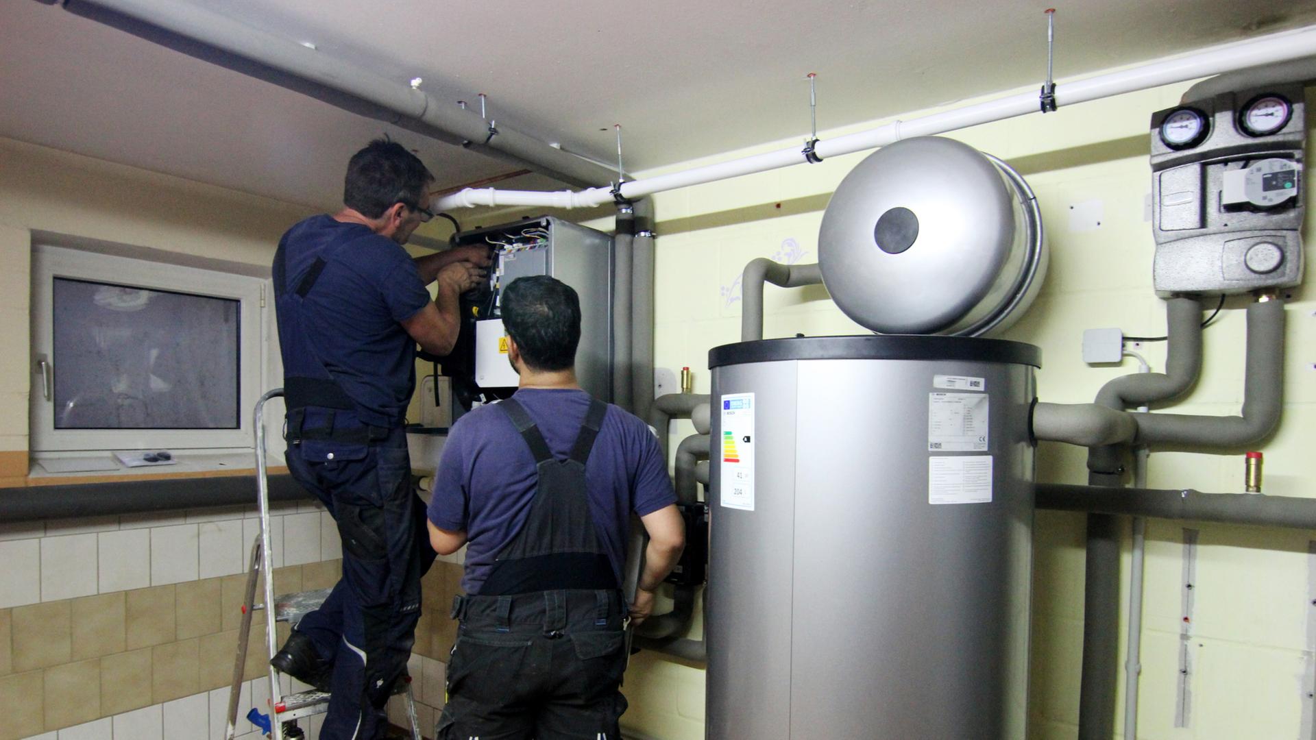 Handwerker stellen eine gerade installierte Wärmepumpe ein. | dpa