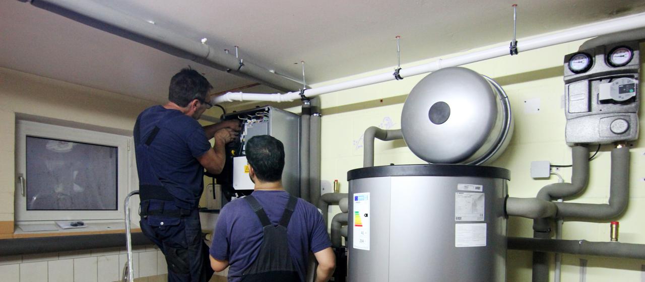 Handwerker stellen eine gerade installierte Wärmepumpe ein.