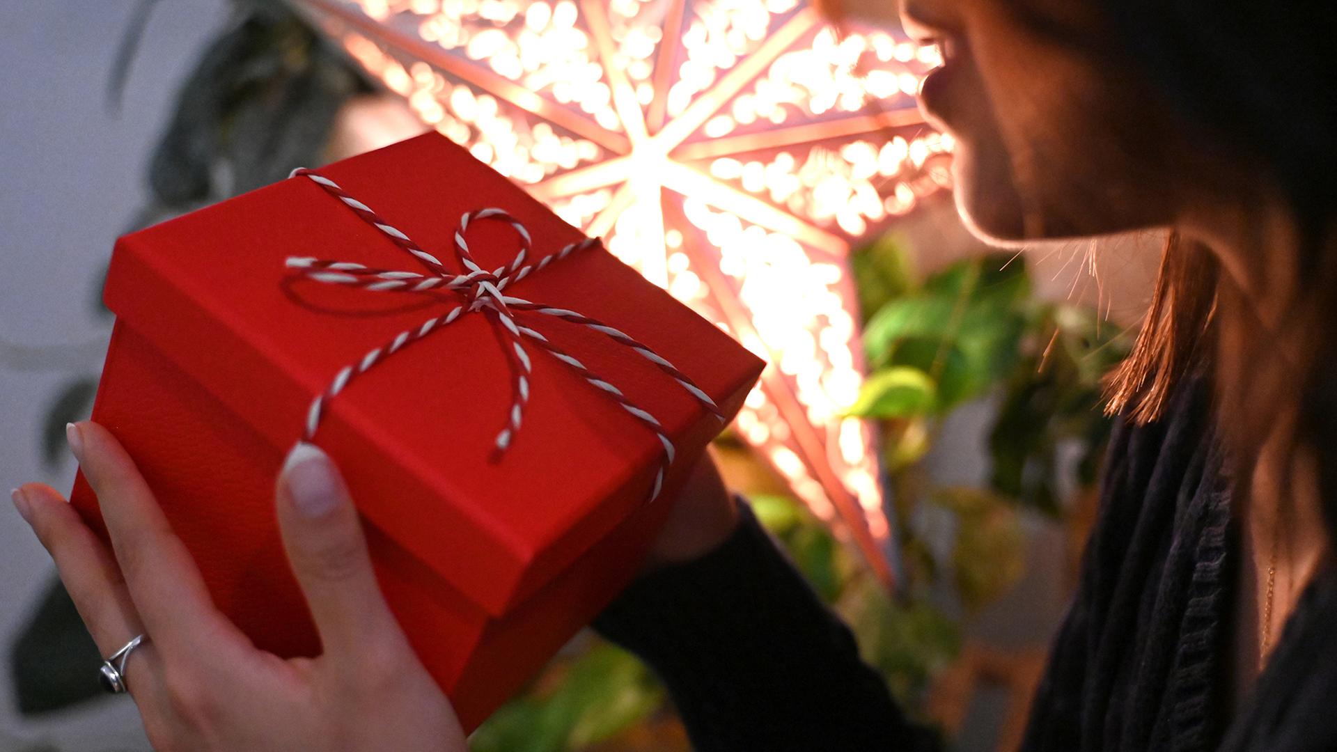 Eine Frau hält eine mit einer Schleife verzierte Geschenkbox.  | dpa