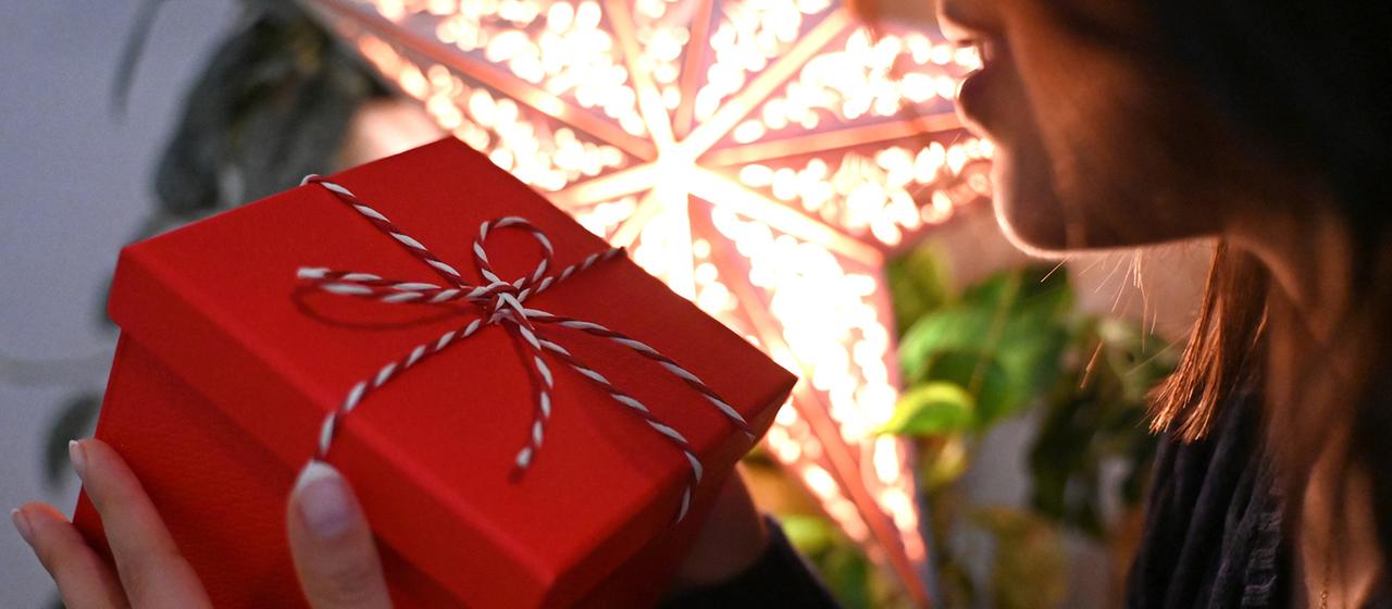 Eine Frau hält eine mit einer Schleife verzierte Geschenkbox. 