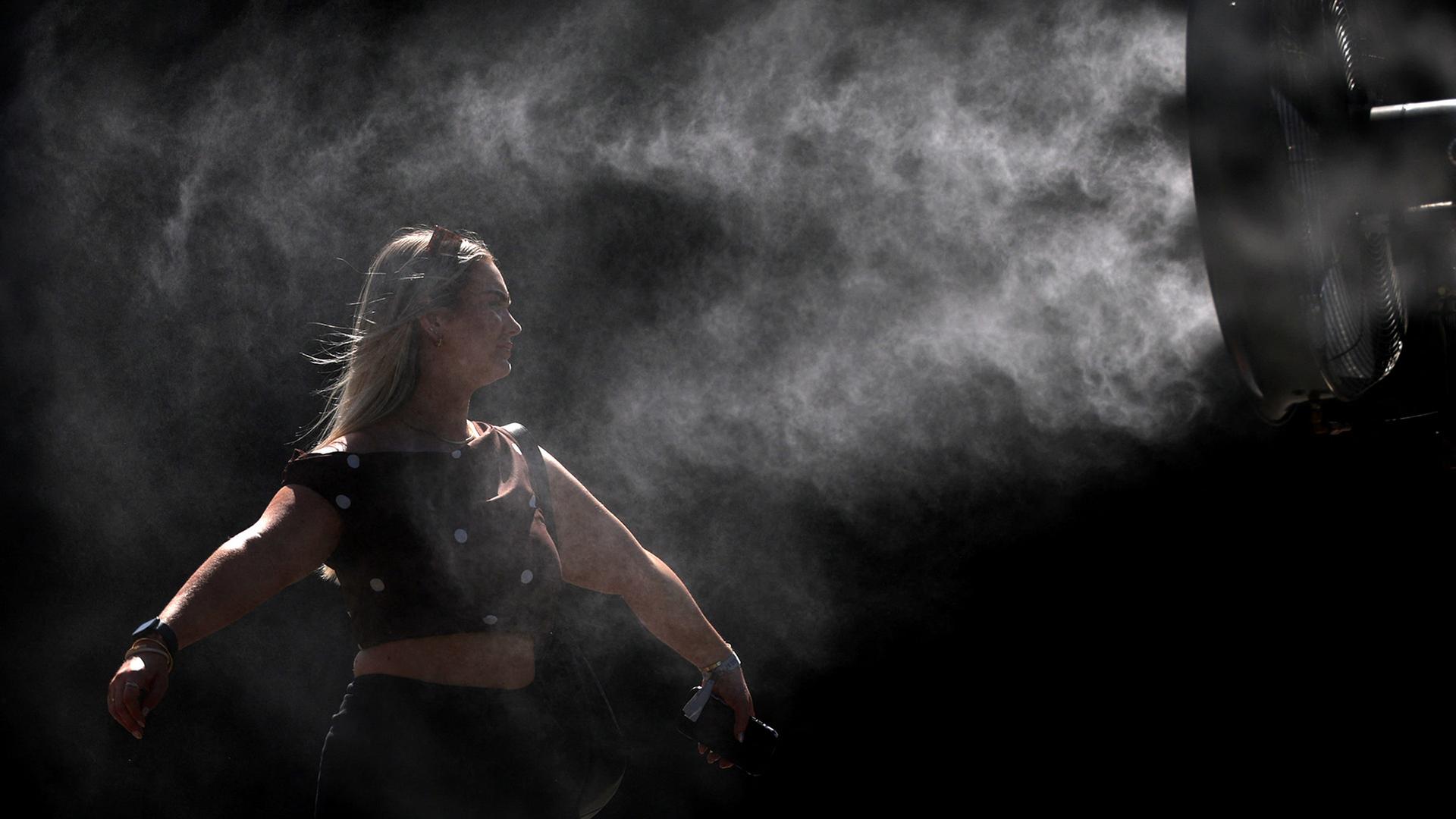 Eine Frau erfrischt sich im SprÃ¼hnebel einer WassersprÃ¼hanlage. | REUTERS