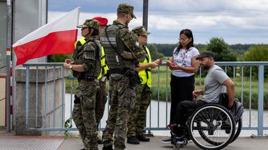 Polnische Grenzbeamte kontrollieren zwei Menschen an der polnisch-deutschen Grenze in Słubice.