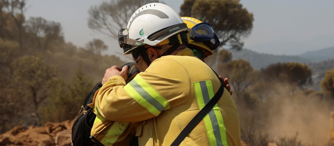 Feuerwehrleute umarmen sich nach den Planierarbeiten in Valdemaqueda zur Bekämpfung der Waldbrände, von denen die Provinzen Ávila und Madrid betroffen sind.