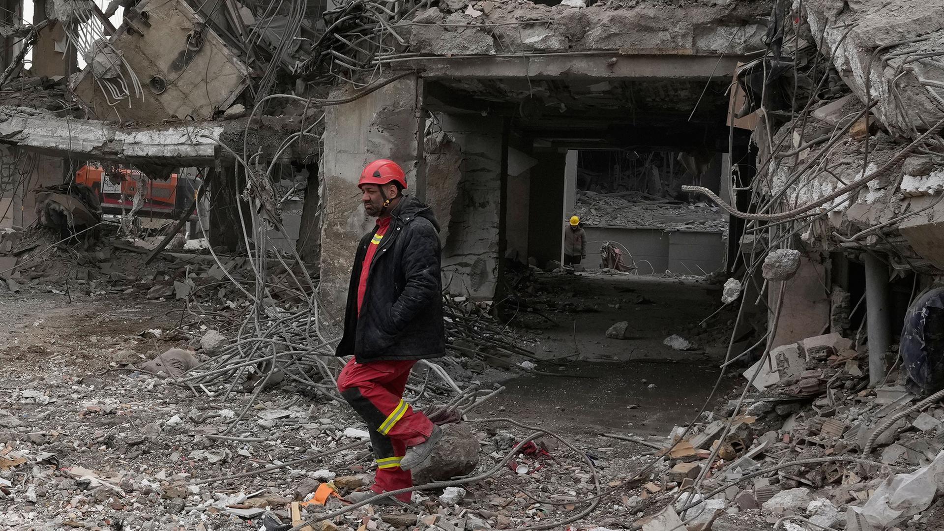 Einsatzkräfte suchen in den Trümmern eines Wohnhauses. | Vahid Salemi/AP/dpa