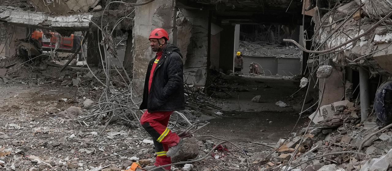 Einsatzkräfte suchen in den Trümmern eines Wohnhauses.