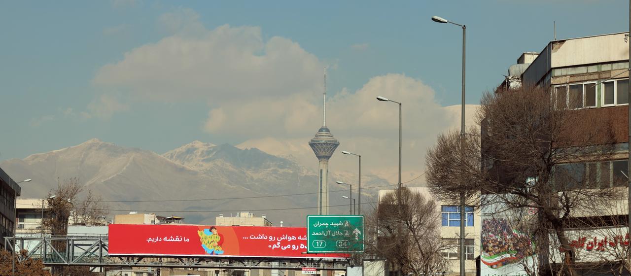Eine Straße mit einem Funkturm und Bergen im Hintergrund.