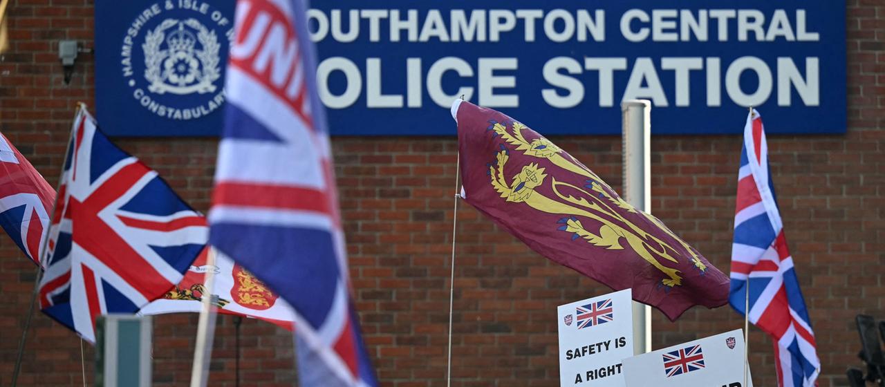 Menschen demonstrieren mit Nationalflagge vor der Polizei Southampton