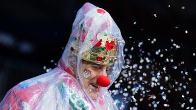 Ein Karnevalist mit Regenschutz in Köln