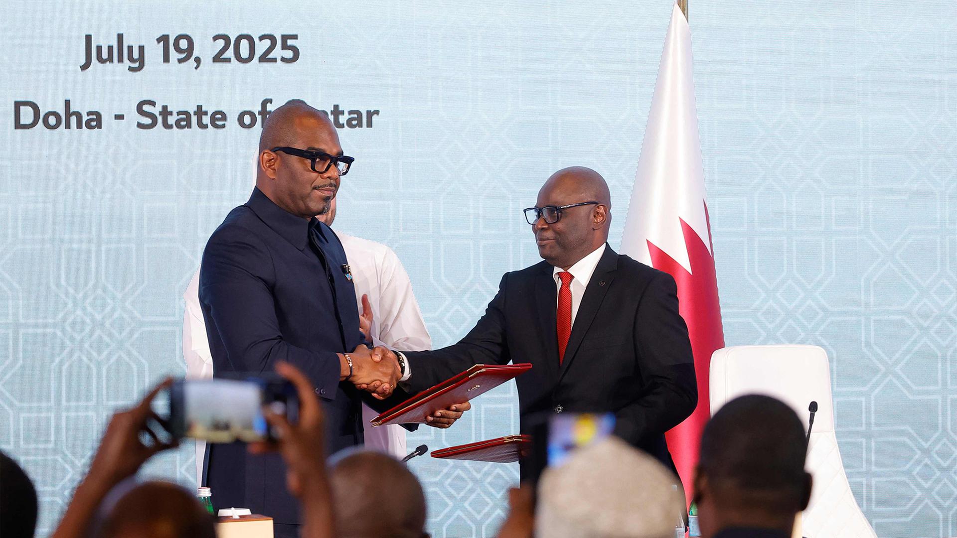 Sumbu Sita Mambu (links) und Benjamin Mbonimp (rechts) geben sich die Hände. | AFP