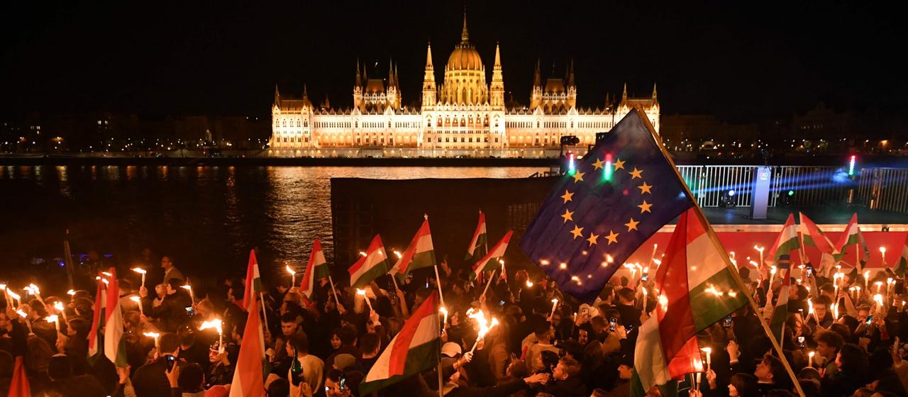 Magyar-Anhänger mit einer EU- und einer Ungarn-Flagge vor Parlamentsgebäude in Budapest