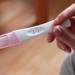 Eine Frau hält einen positiven Schwangerschaftstest in der Hand.