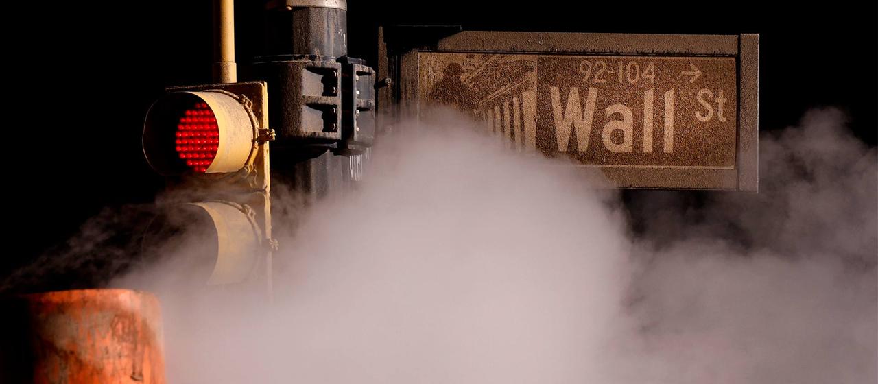 Dampf aus einem Rohr strömt unter einem Schild für die Wall Street in der Nähe der New Yorker Börse hindurch.