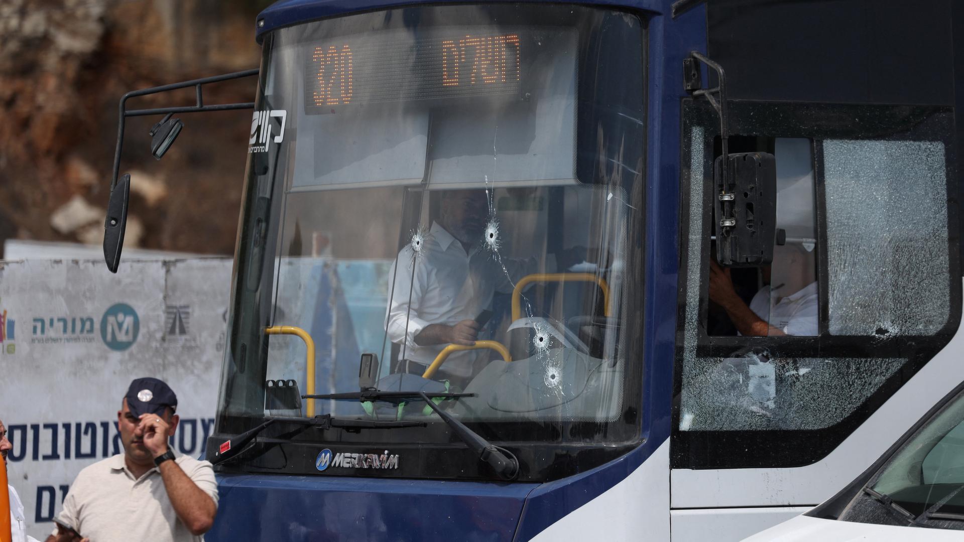 Polizisten untersuchen einen Bus mit Einschusslöchern in der Windschutzscheibe in Jerusalem. | REUTERS