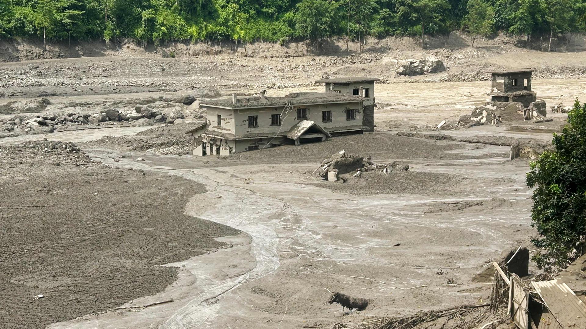 Ein Haus steht nach Sturzfluten in Nepal teilweise im schlammigen Wasser. | AFP