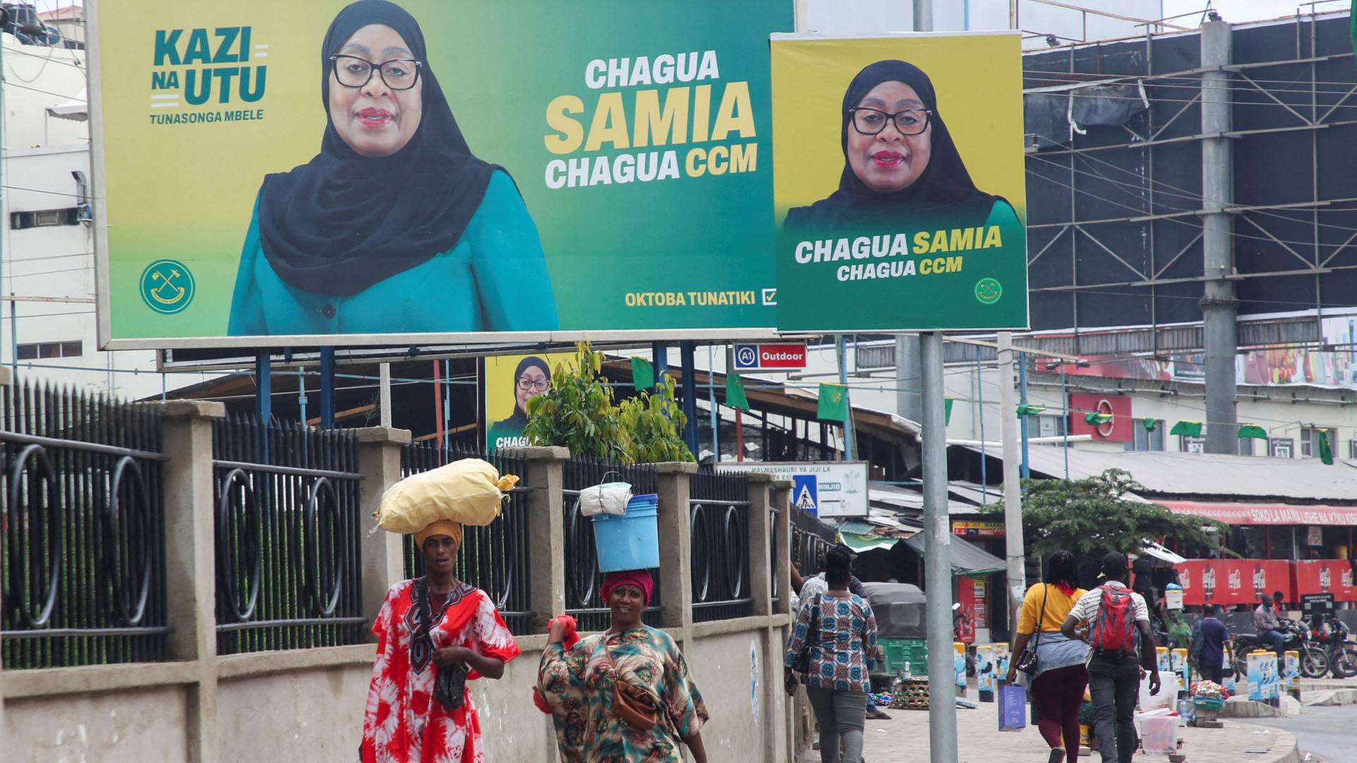 Menschen gehen an Wahlplakaten der tansanischen Präsidentin Samia Suluhu Hassan vorbei. | REUTERS