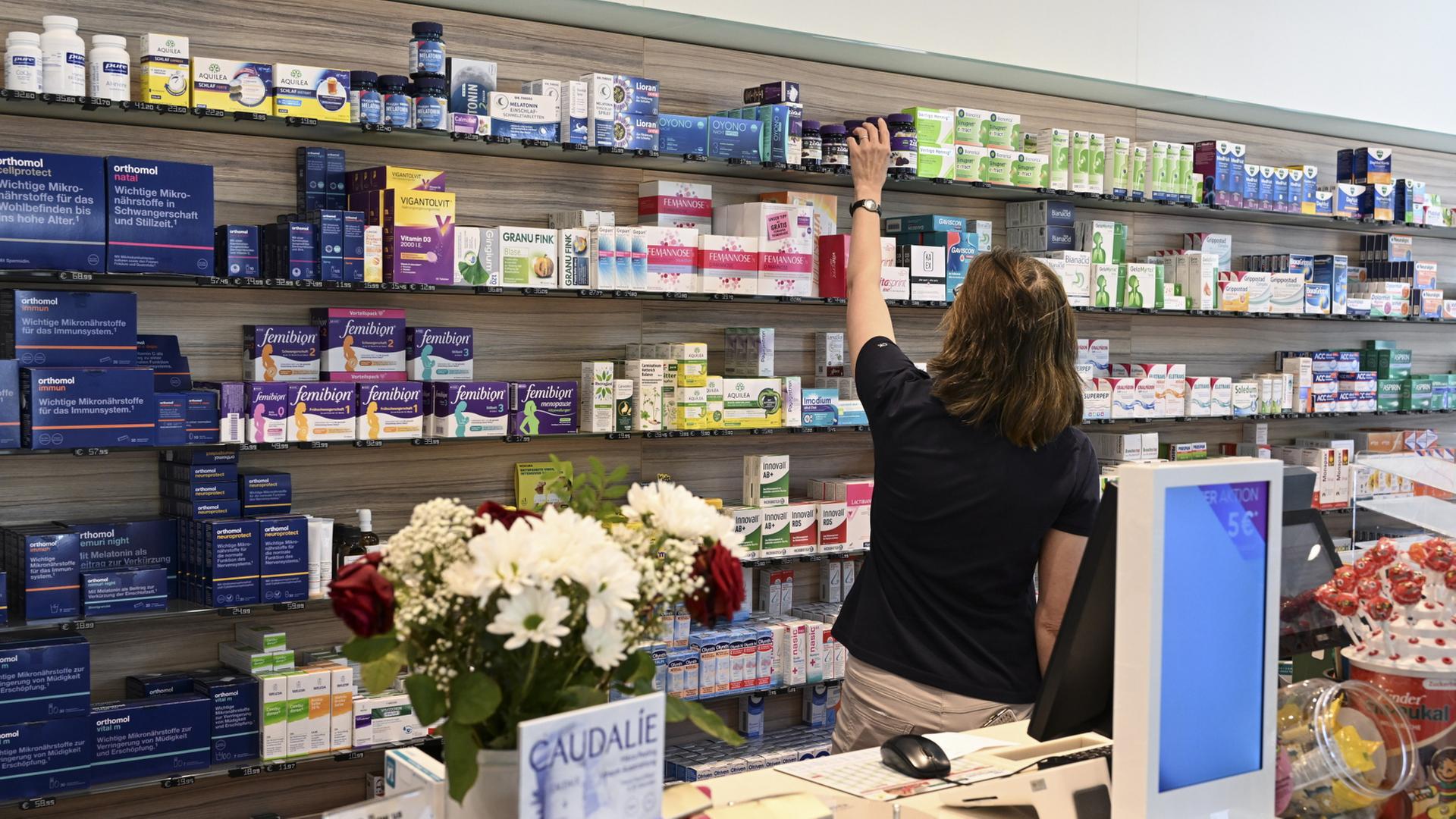 Eine Mitarbeiterin in einer Apotheke greift nach freiverkäuflichen Arzneimitteln. | dpa