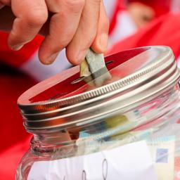 Ein Mann steckt einen Geldschein in ein Spendenglas.