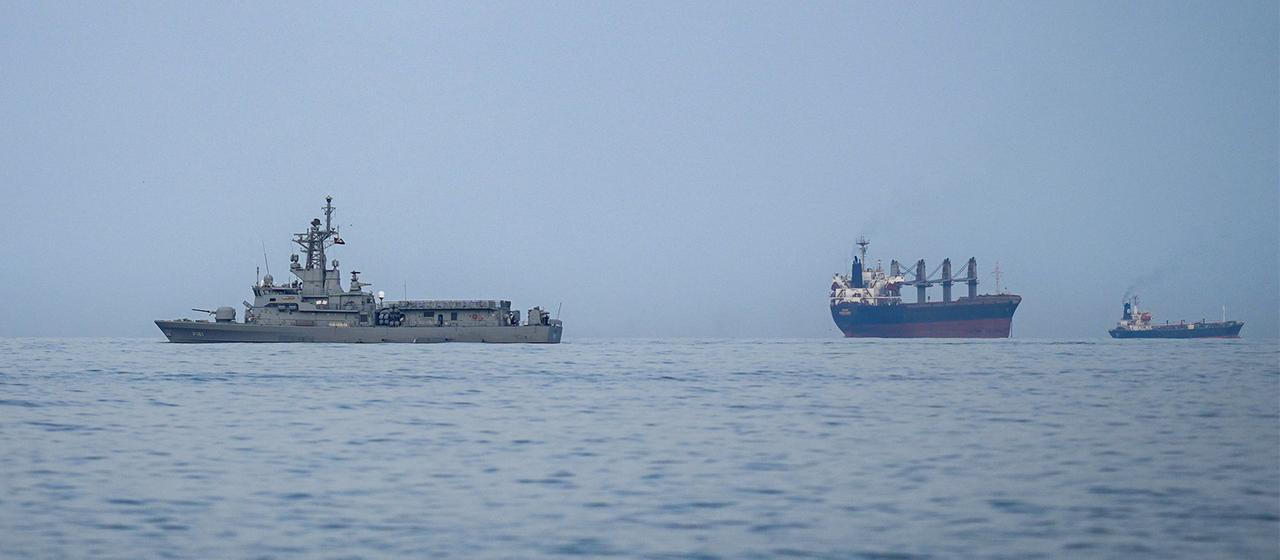 Ein Schiff der Marine der Vereinigten Arabischen Emirate neben Frachtschiffen und Öltankern.