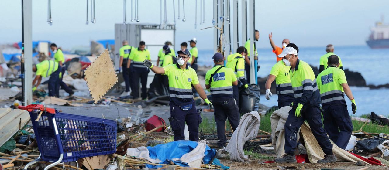 Arbeiter räumen Trümmer aus dem provisorischen Lager "El Guano" in der Nähe des Trampolin-Strandes in der spanischen Enklave Ceuta in Nordafrika weg.