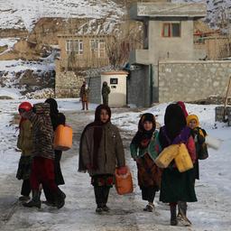 Kinder tragen an einer schneebedeckten Straße Behälter, um Trinkwasser zu holen.