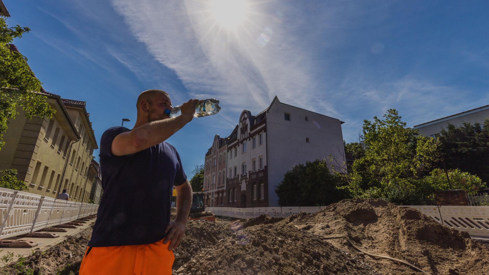 Ein Arbeiter einer Tiefbaufirma trinkt auf der Baustelle. | Frank Hammerschmidt/dpa