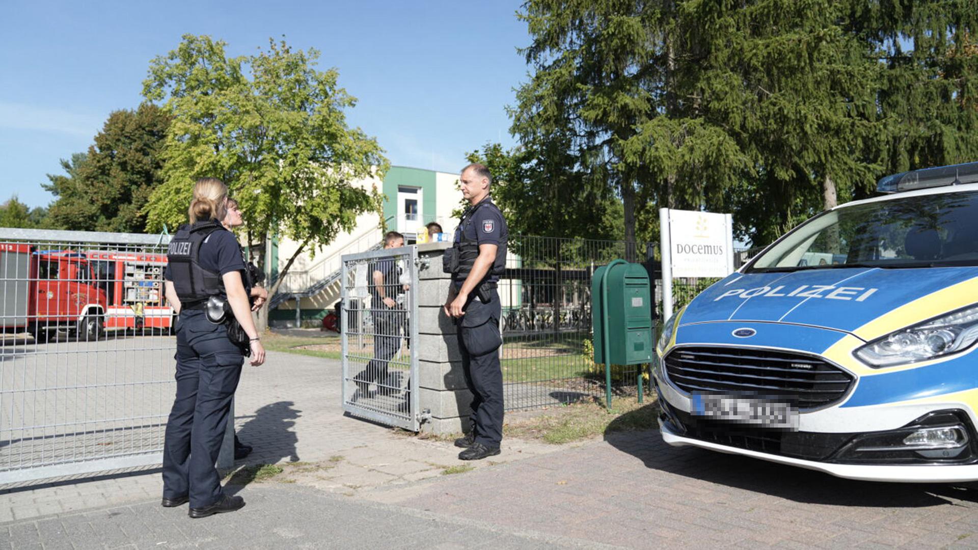 Polizisten stehen vor einer Schule. Bei einer Gewalttat an einer Schule in Gosen-Neu Zittau sind nach Informationen der Deutschen Presse-Agentur eine Frau und ein Mann getötet worden. (Quelle: dpa/Genolet) | dpa/Genolet