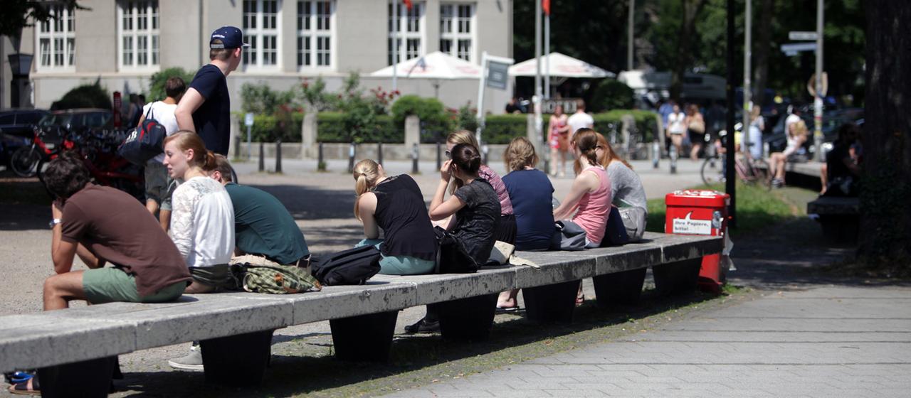 Junge Menschen sitzen auf einer Bank.